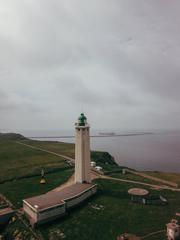 A striking aerial view of Phare d'Antifer lighthouse on a cloudy day in France, overlooking the sea.