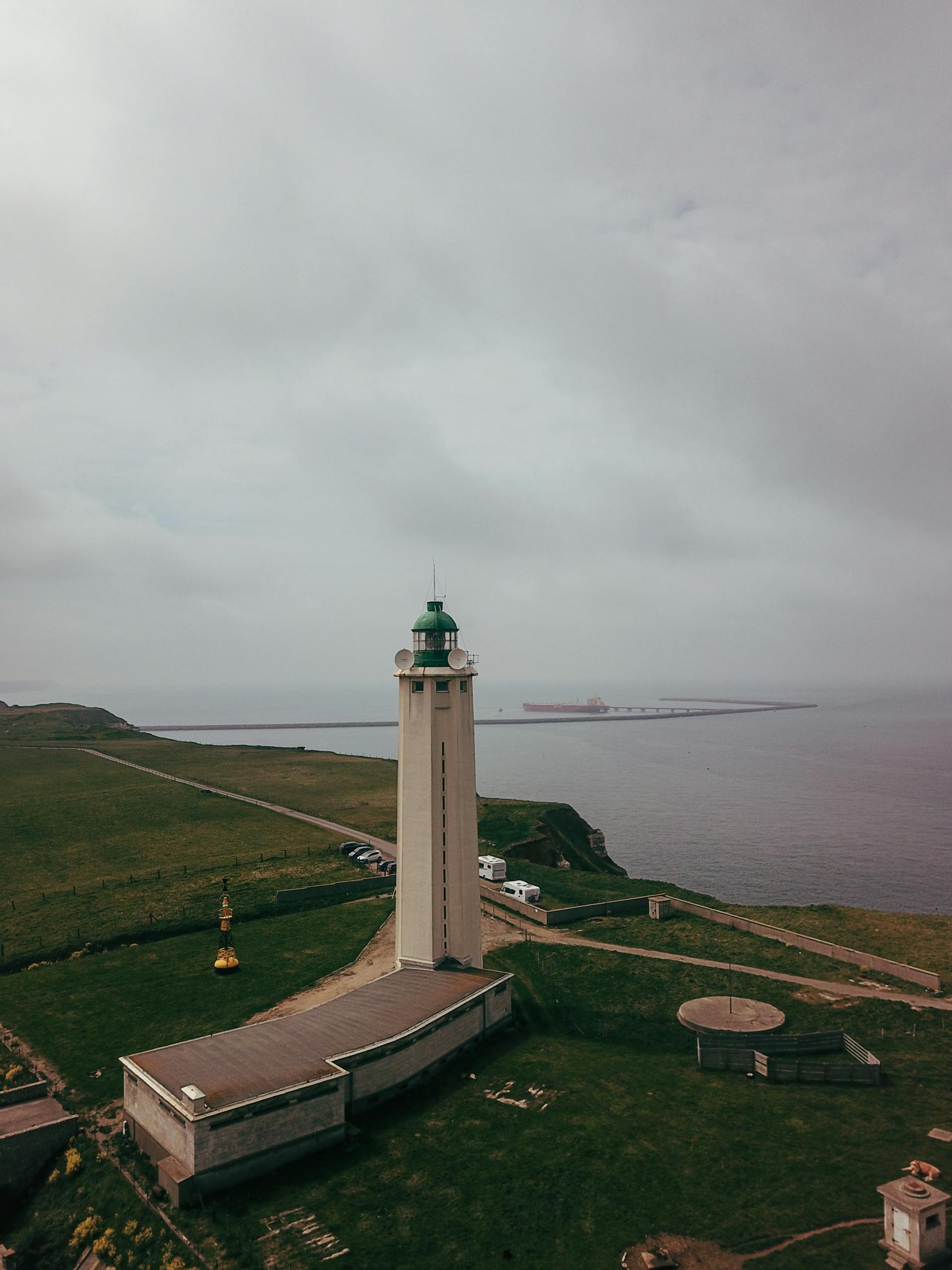 A striking aerial view of Phare d'Antifer lighthouse on a cloudy day in France, overlooking the sea.