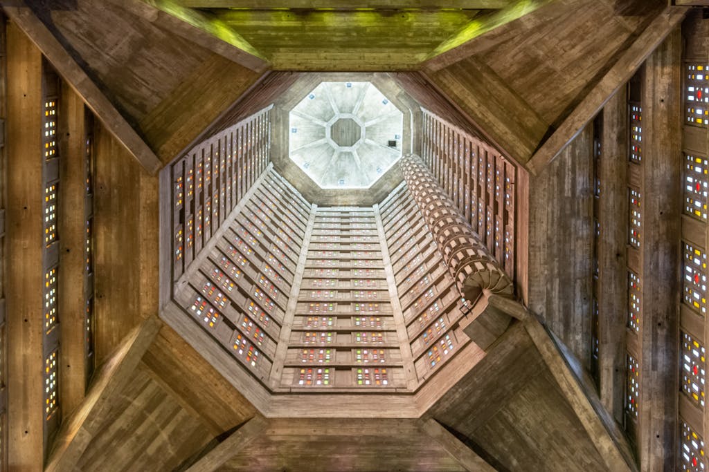 Upward view of St. Joseph's Church tower in Le Havre, showcasing stained glass and concrete structure.