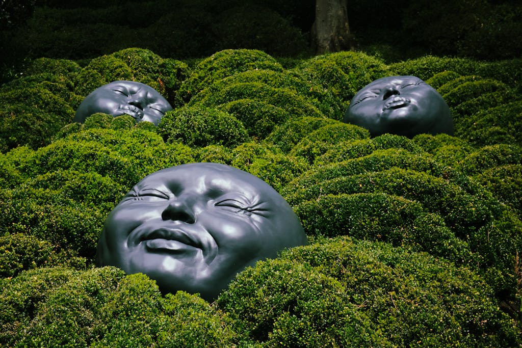 Unique black sculptures nestled in lush greenery at Étretat Gardens, France, showcasing artistic creativity.