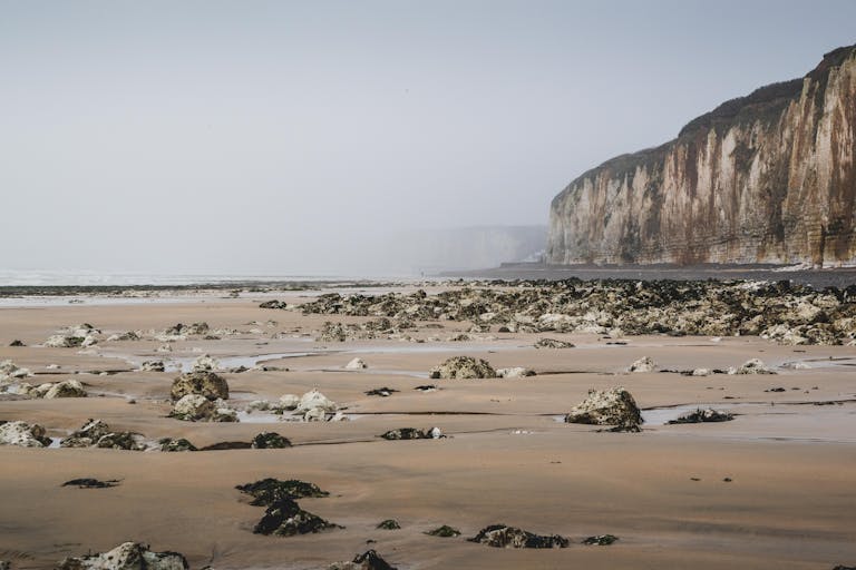 Explore the serene misty beach and striking cliffs at Veules-les-Roses in Normandy, France.