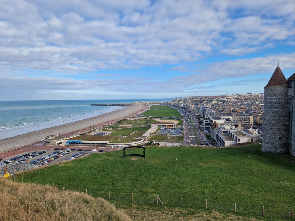 Aerial view of Dieppe, France showcasing the beach, town, and coastline under a cloudy sky.