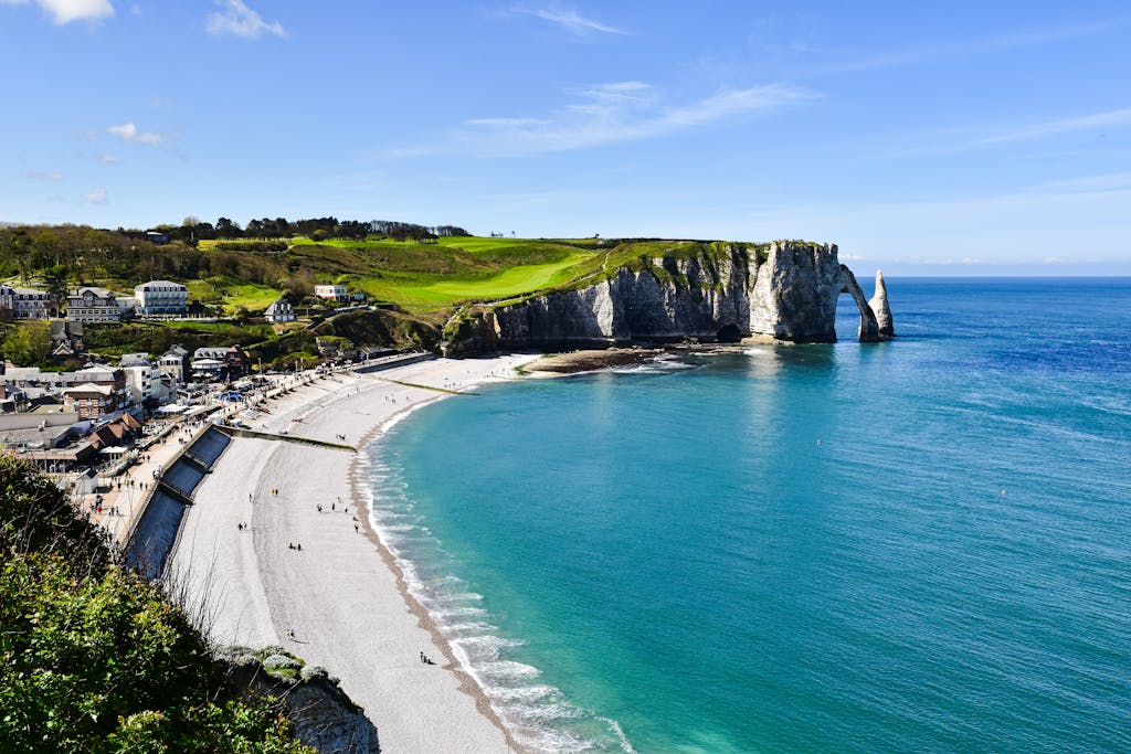 Scenic view of Etretat's white cliffs and turquoise sea on a sunny summer day, France.