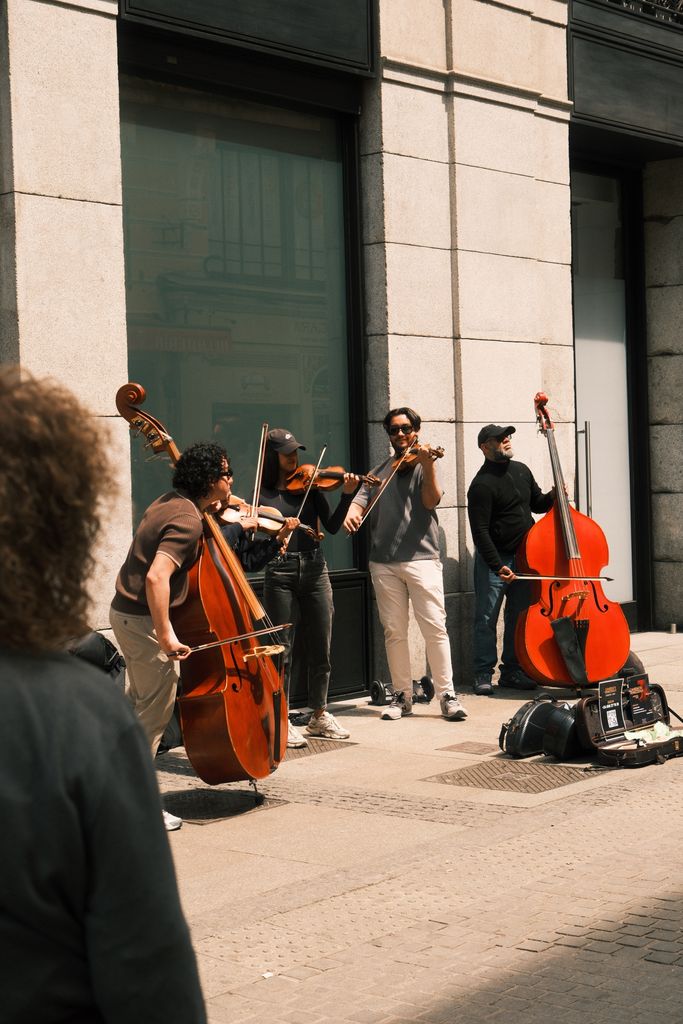 A vibrant street performance with musicians playing classical instruments under the warm sun.