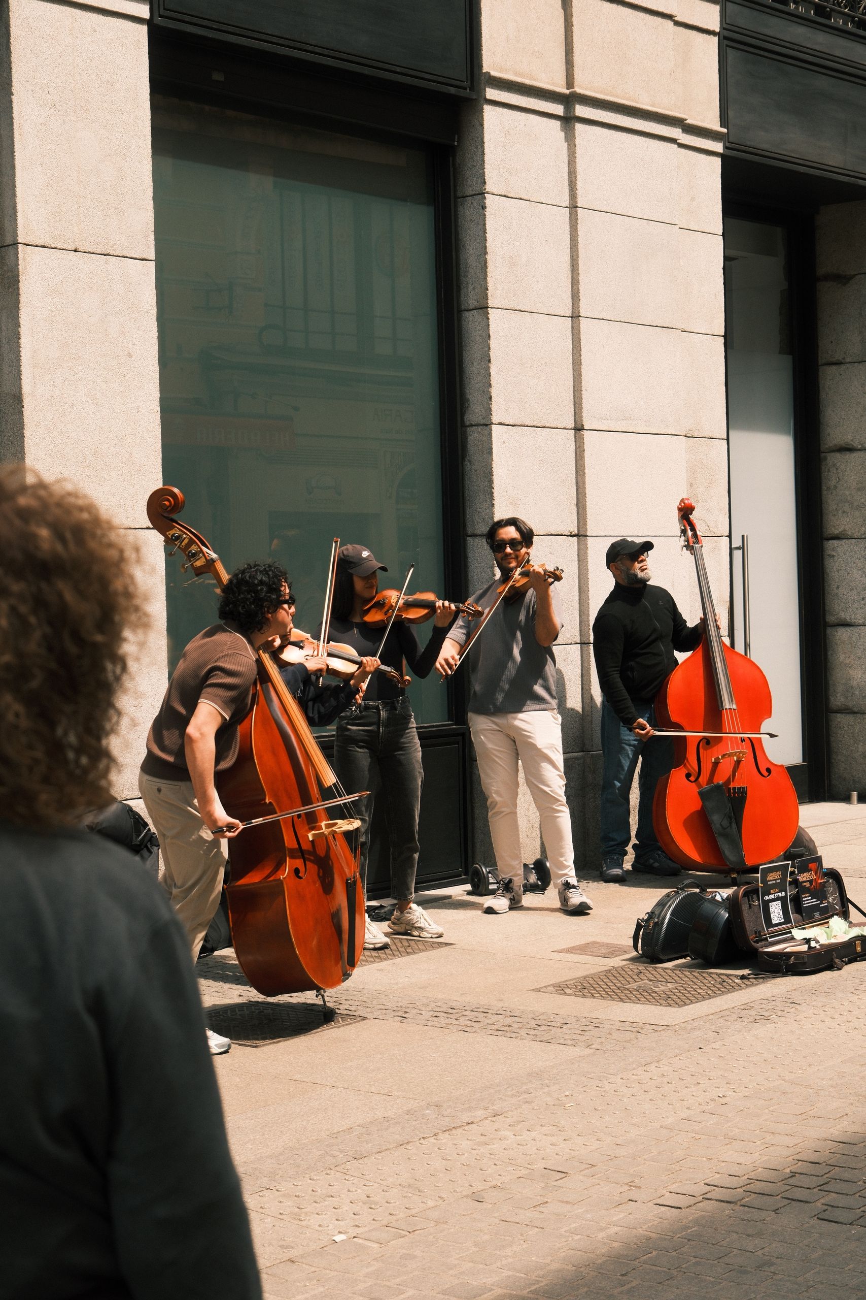 A vibrant street performance with musicians playing classical instruments under the warm sun.
