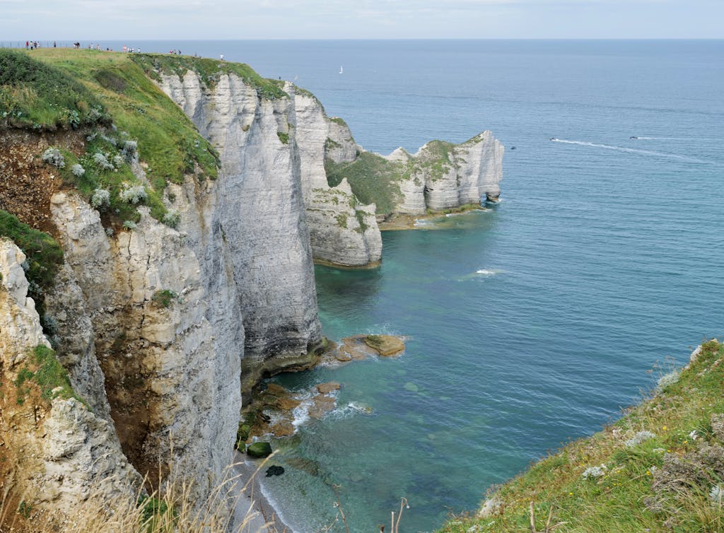 Explore the stunning cliffs of Étretat, Normandie with azure waters and lush greenery.
