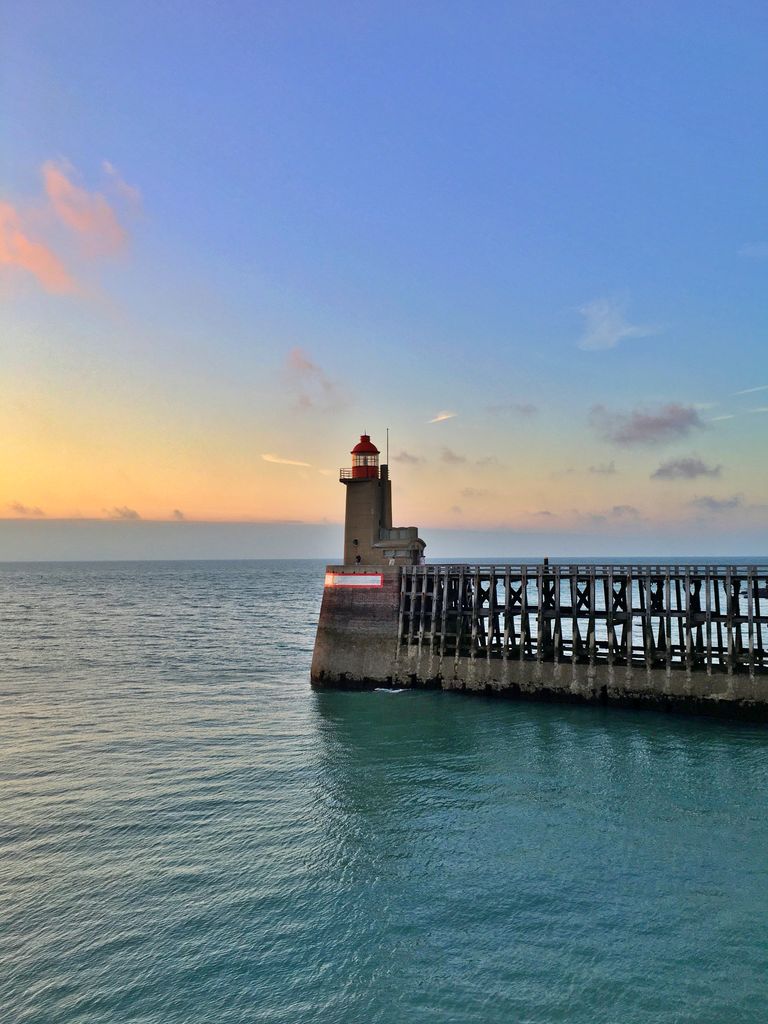A serene sunset view of the lighthouse at Fécamp pier, Normandy, France.